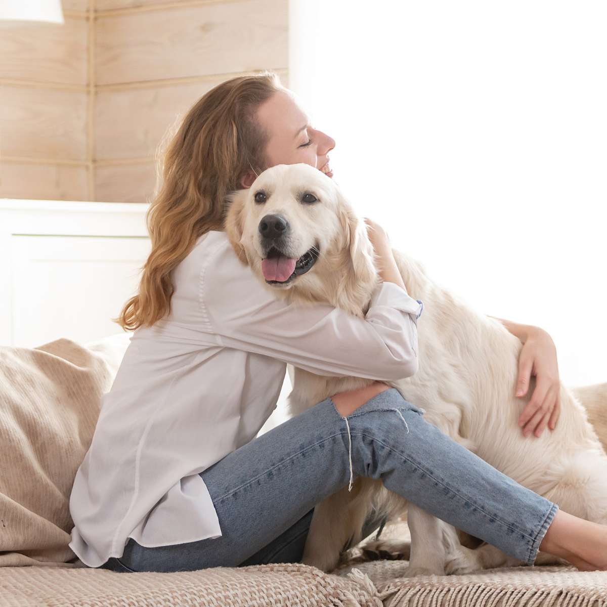 A golden retriever being hugged by its female owner